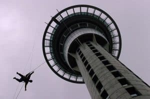 Iconic Sky Tower in Auckland, New Zealand, with a person bungee jumping from the observation deck.