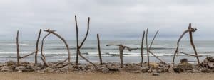 Unique driftwood sculptures on Hokitika Beach with ocean backdrop.