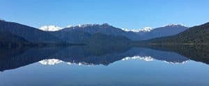 Reflection of Lake Kaniere with snow-capped mountains in New Zealand.