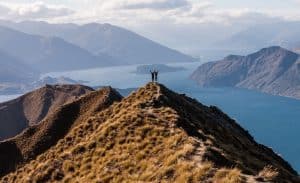 Hikers standing at the peak of Roys Peak with panoramic mountain views.