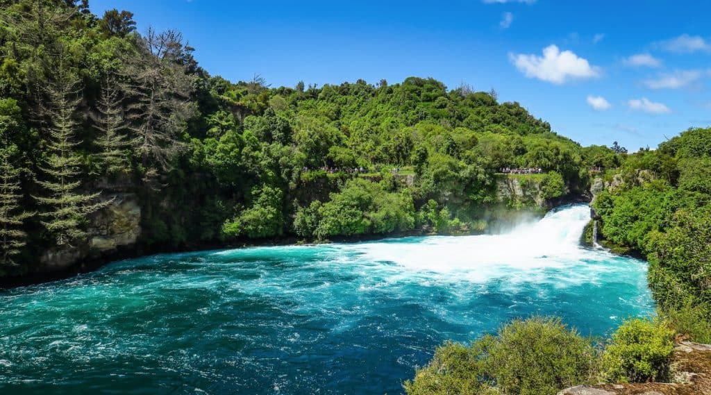 A powerful view of the churning, vibrant turquoise waters of Huka Falls rushing through a narrow volcanic rock canyon on the Waikato River near Taupō.