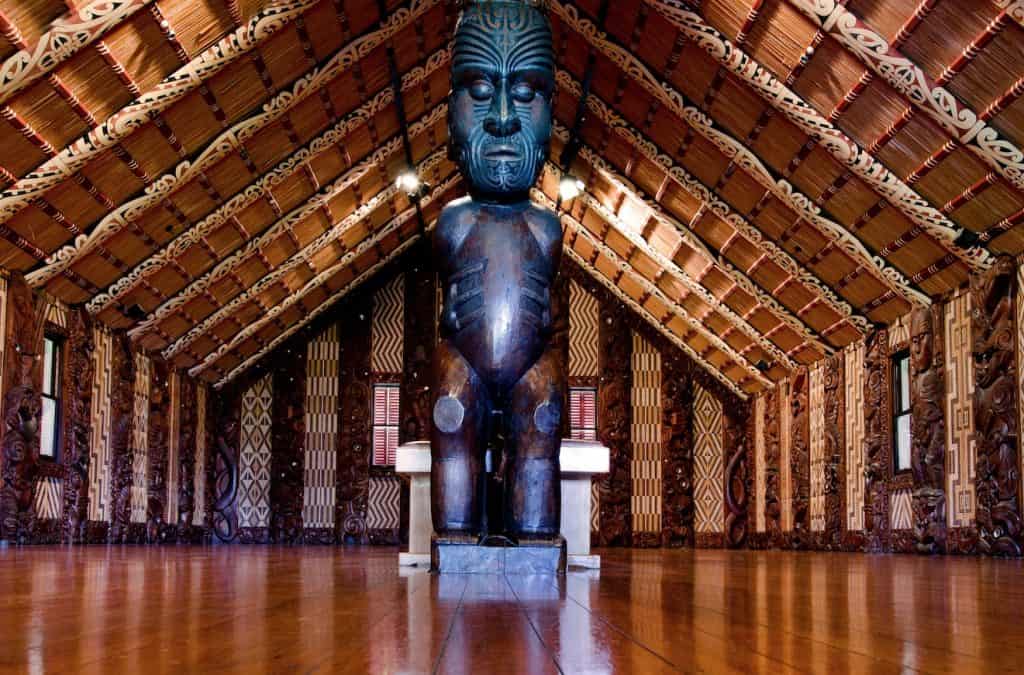The intricately carved wooden interior of Te Whare Rūnanga (the carved meeting house) at the Waitangi Treaty Grounds, showing traditional Māori whakairo (carvings) and tukutuku panels.