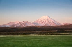 Panoramic view of the volcanic landscape of Tongariro National Park basking in warm afternoon sun, showcasing Mount Ngauruhoe and rugged alpine terrain.
