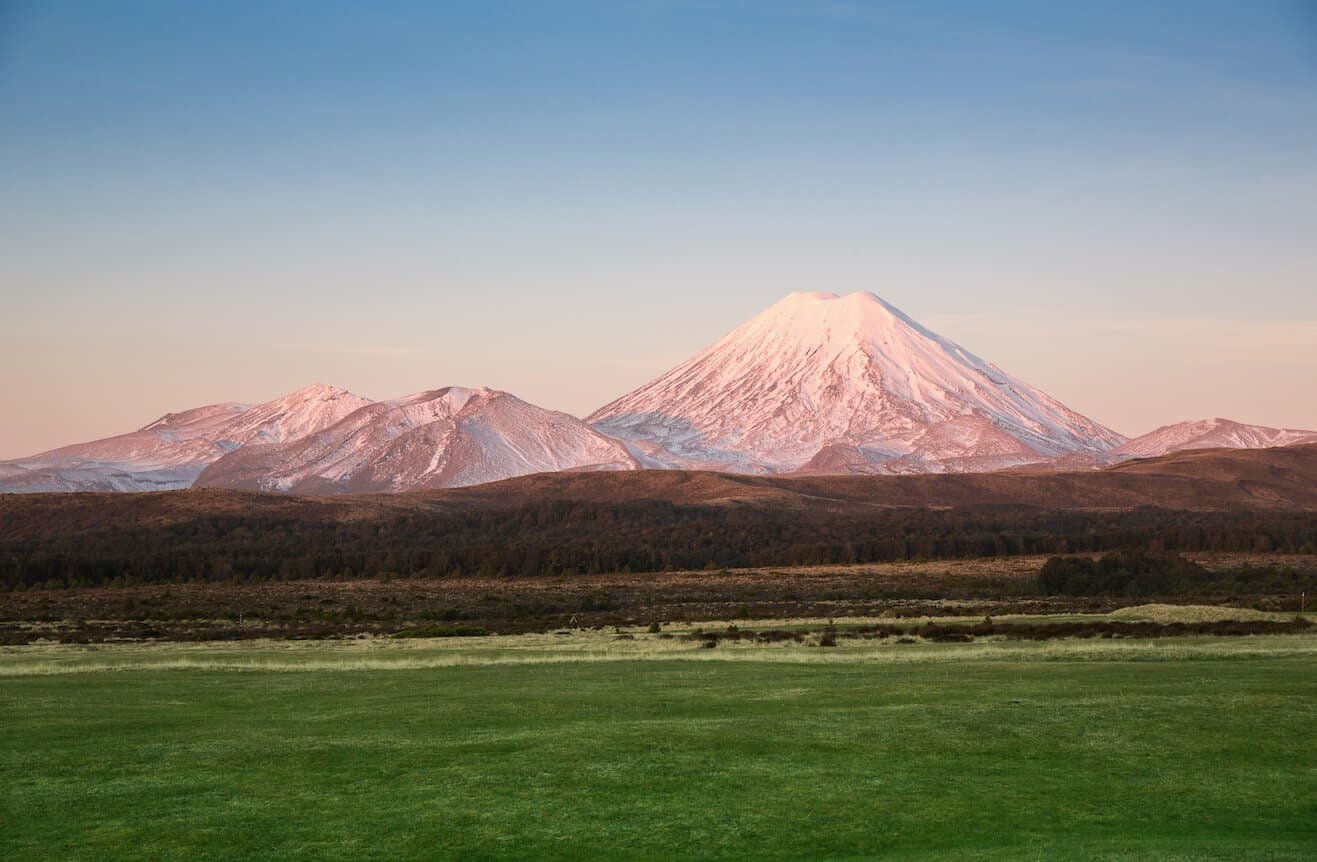 Panoramic view of the volcanic landscape of Tongariro National Park basking in warm afternoon sun, showcasing Mount Ngauruhoe and rugged alpine terrain.