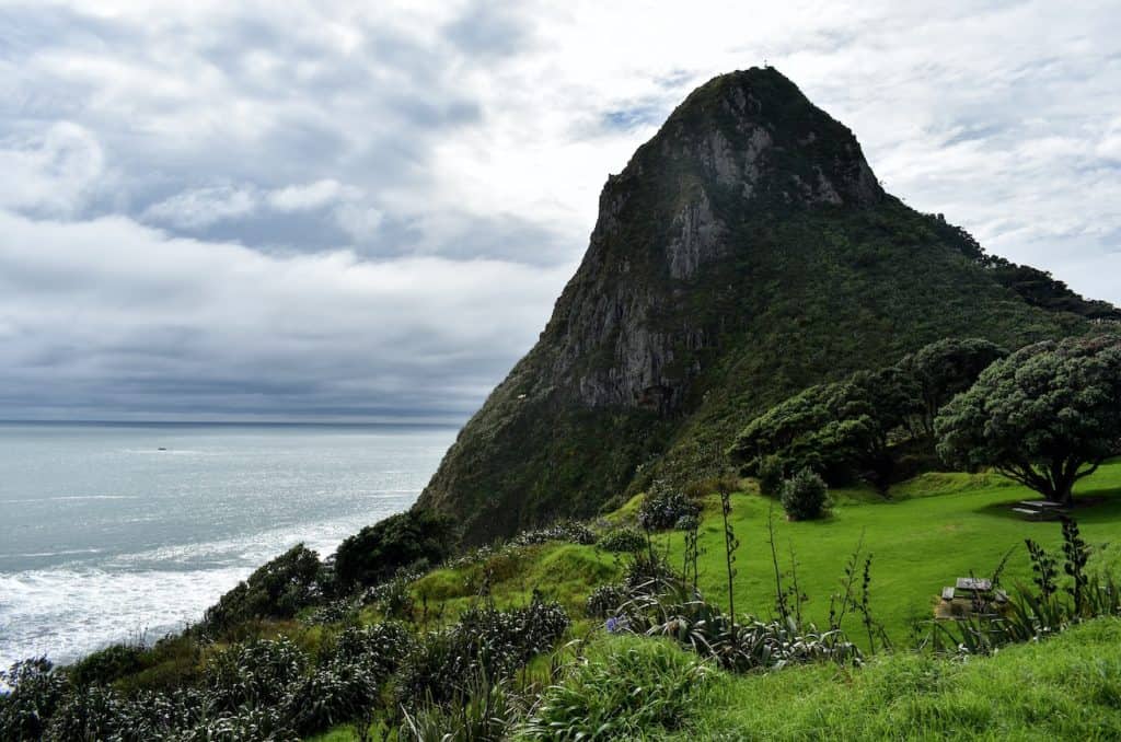 The sheer volcanic plug of Paritutu Rock rising 156 metres above the Taranaki coastline, its steep grass and bush-covered flanks dropping dramatically to the Tasman Sea below New Plymouth.
